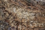 Vinařická hora - pohled na hlavní stěnu lomu - světlá vrstva pyroklastik s xenolity - detail prohlubně a světlejší horniny - opuky, horní části obrázku malý lávový proud mezi pyroklastiky
